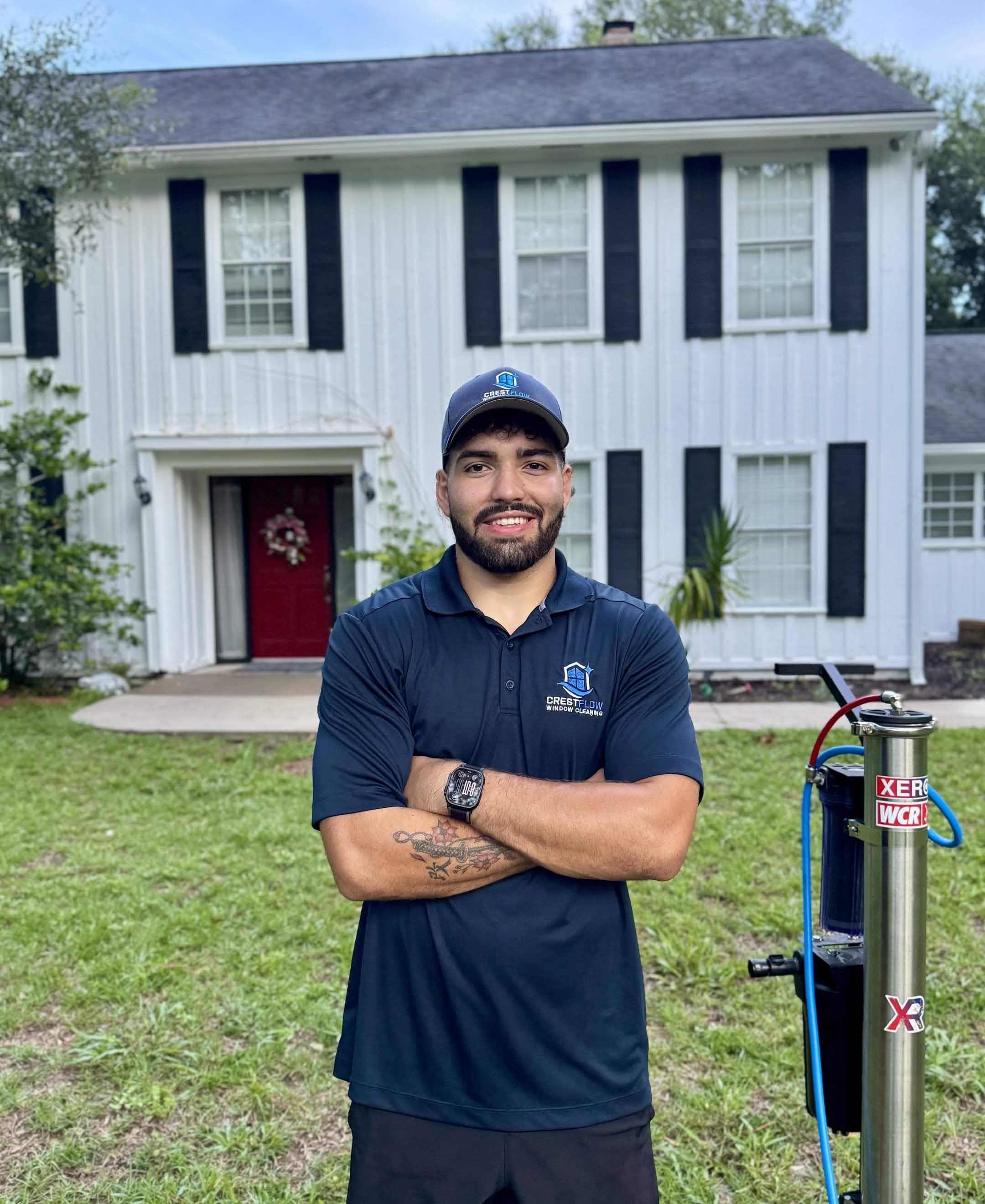 CrestFlow owner in a branded polo standing in front of a Palm Coast home beside his purified-water filtration system