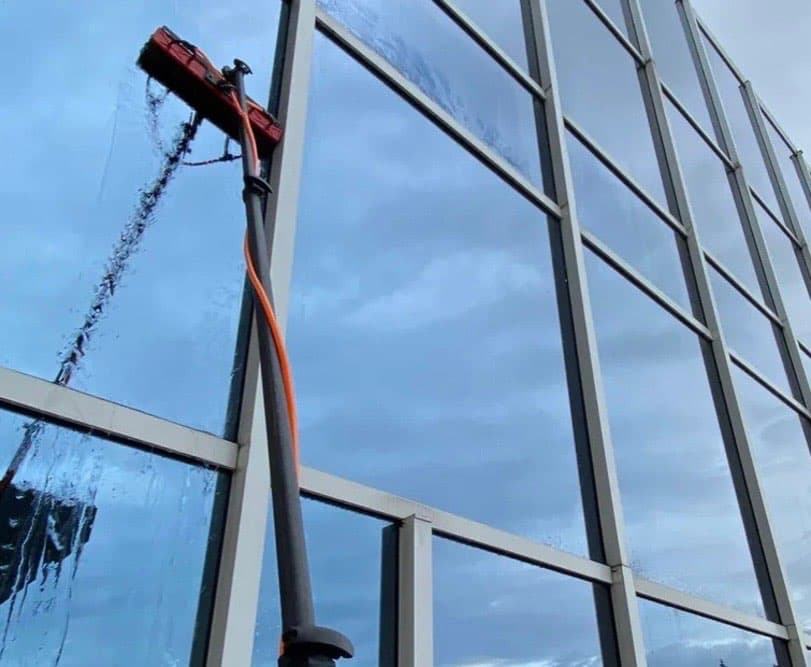 CrestFlow water-fed pole washing the upper panes of a multi-story commercial glass curtain wall