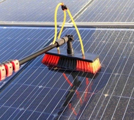 Soft-bristle water-fed brush washing dirt off a rooftop solar panel